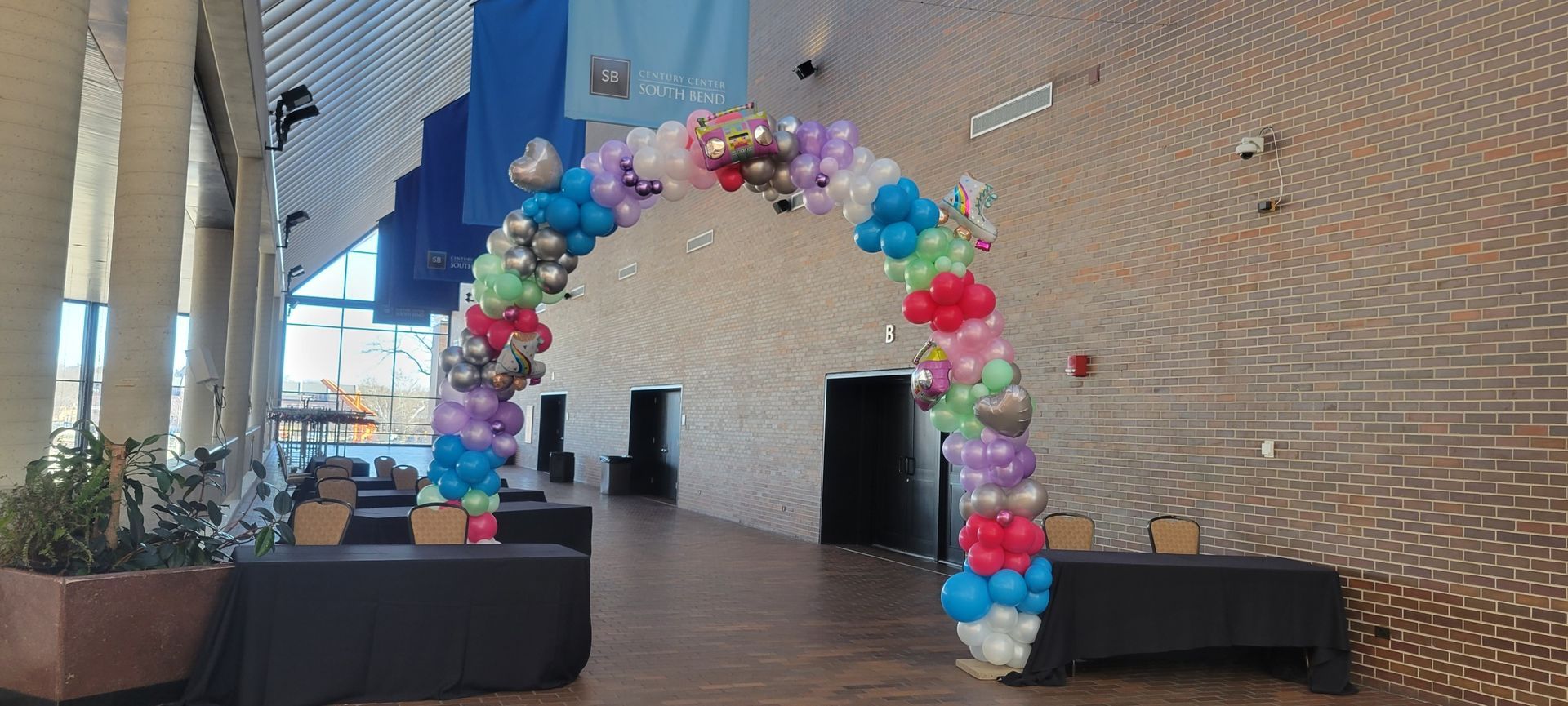 There is a large arch made of balloons in the middle of a room.