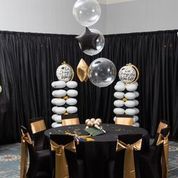 A room with a table and chairs decorated with balloons.