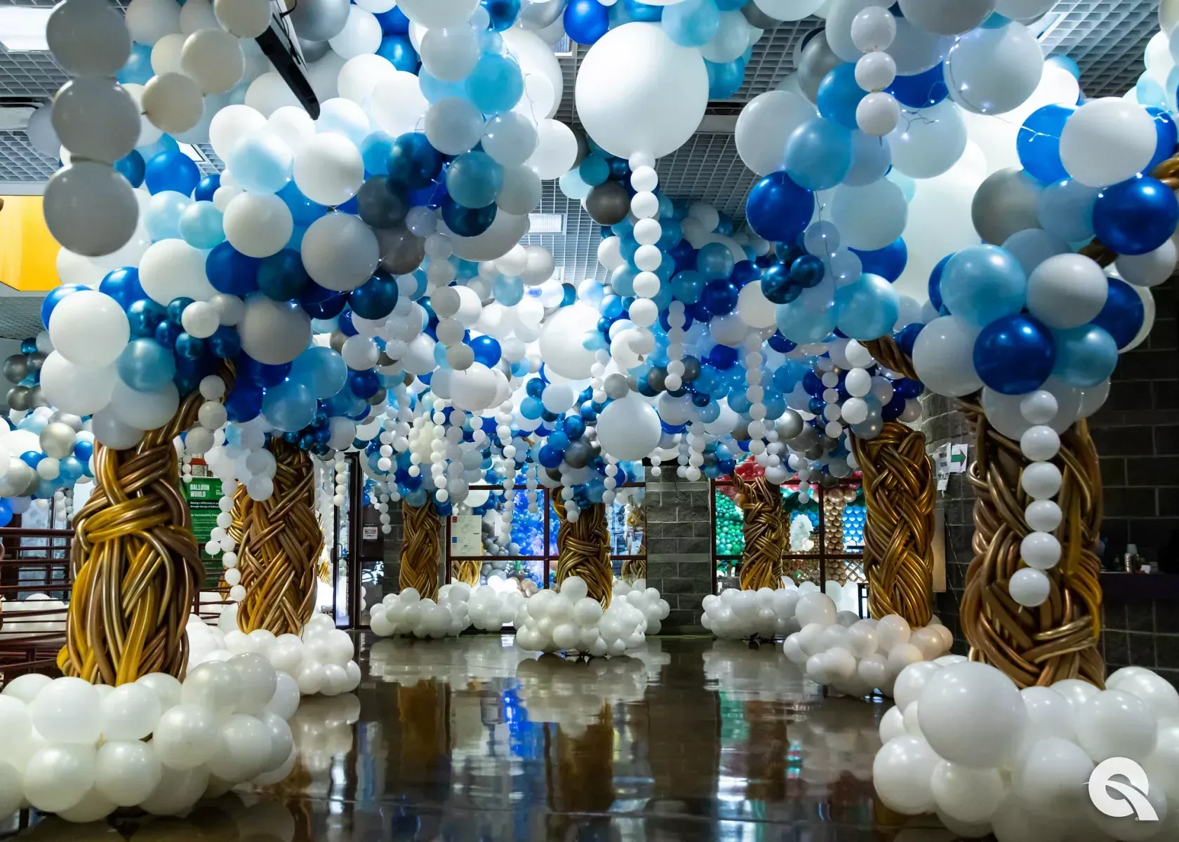A room filled with lots of blue and white balloons shaped like a forest of trees