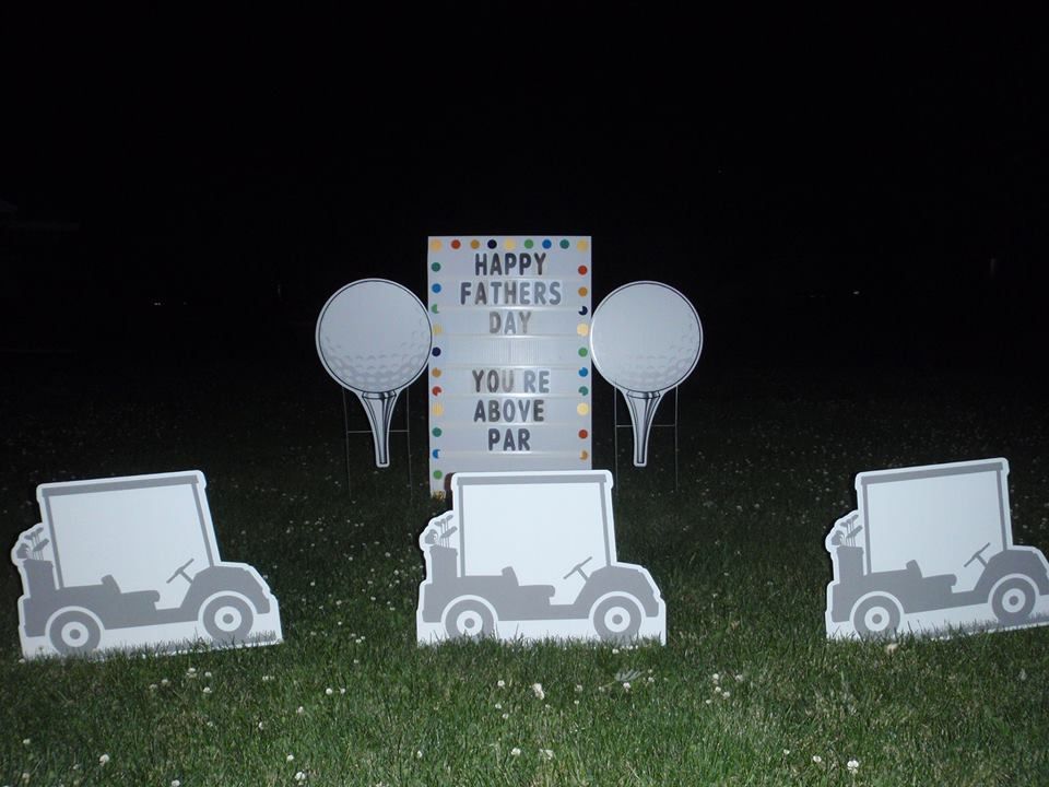 A sign that says happy fathers day on it. Golf themed yard card.