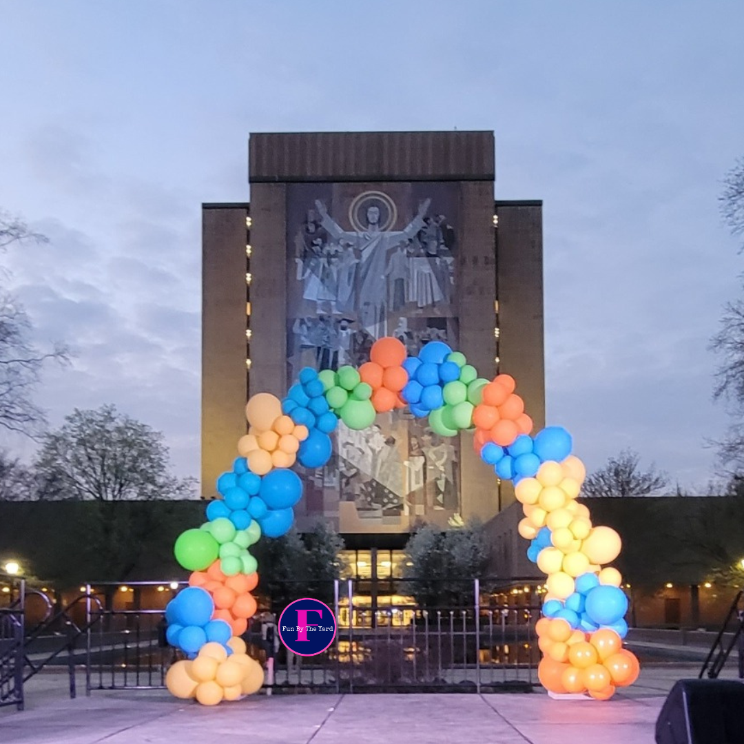 A colorful balloon arch in front of a building with the letter f on it