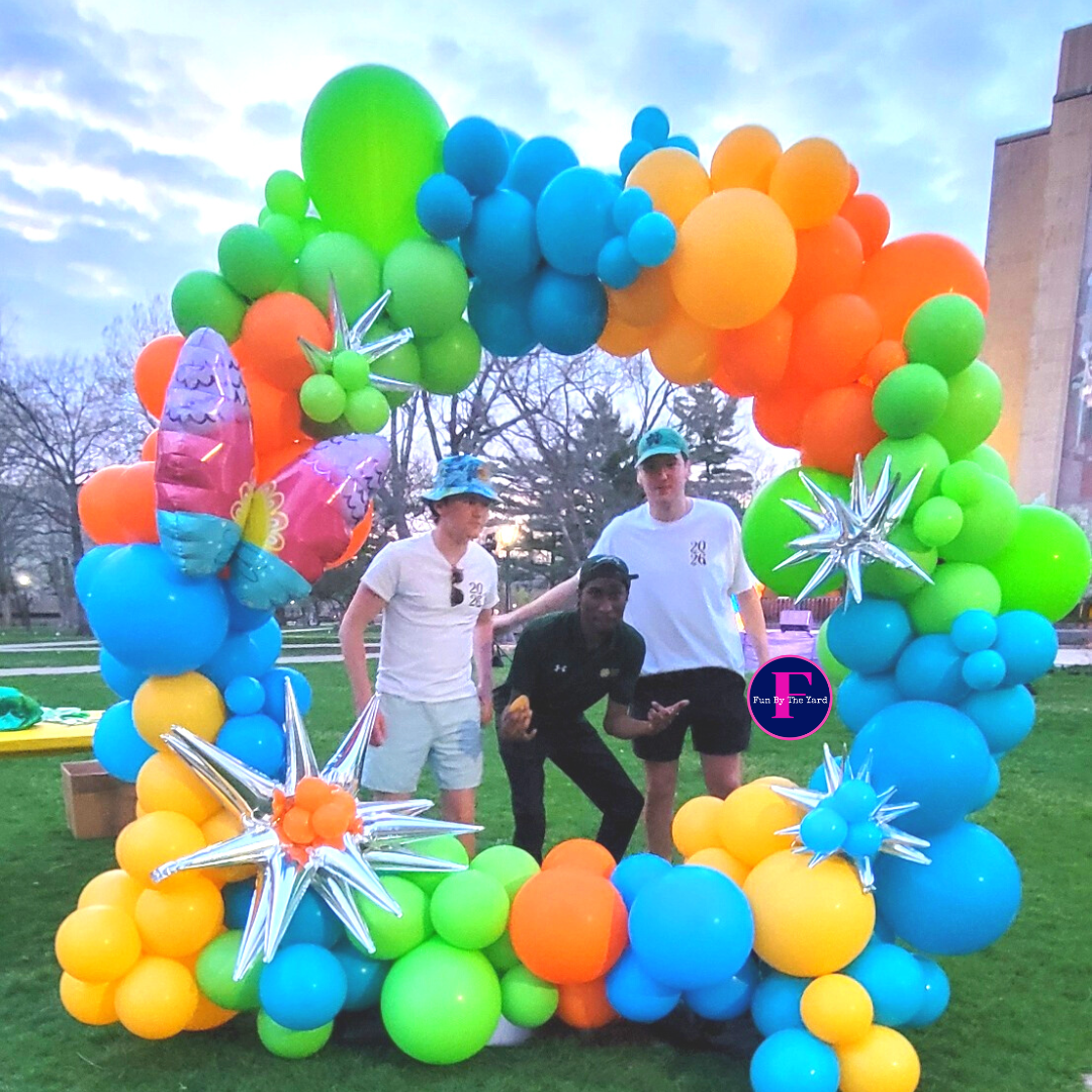 a group of people standing in front of a rainbow colored balloon arch