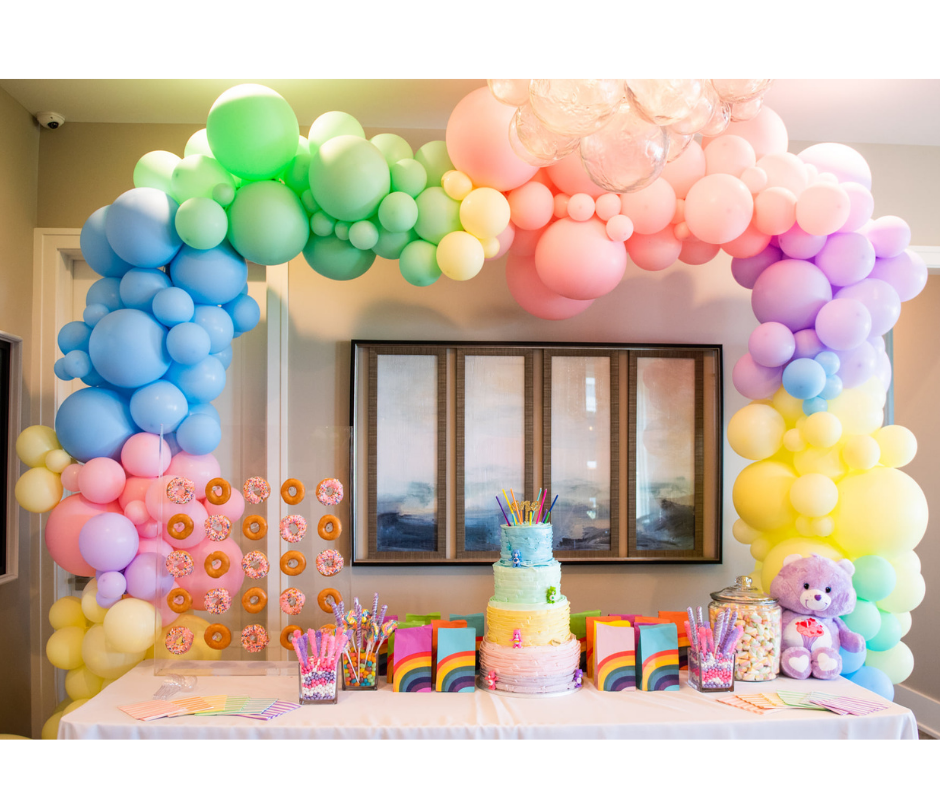 A room decorated with an organic balloon arch and a cake for a birthday party.