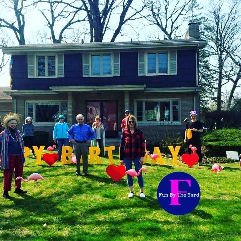 A group of people standing in front of a house decorated for a birthday