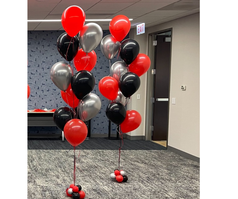Helium balloon bouquets in red , black and silver sitting on top of each other in a room.