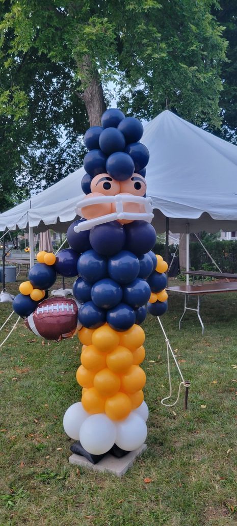A football player statue made out of balloons is holding a football.