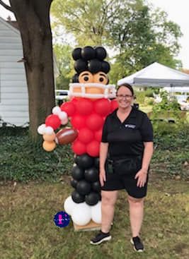 A woman is standing next to a football player made out of balloons.