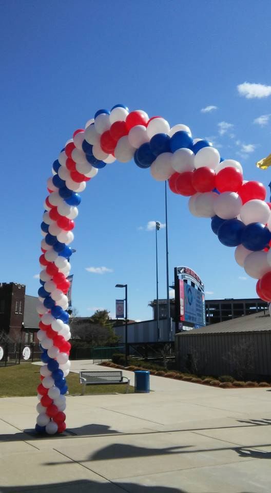 A red white and blue balloon arch with a blue sky in the background