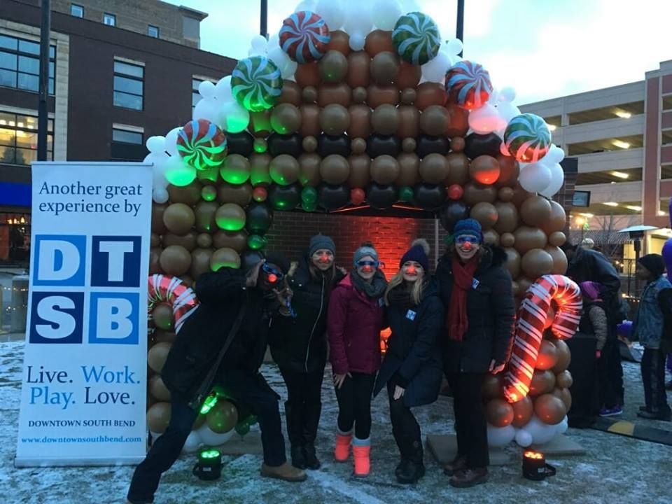 A group of people standing in front of a gingerbread house made of balloons.