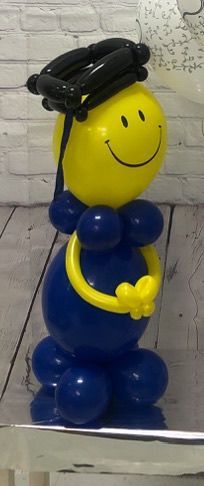 A yellow balloon with a smiley face and a graduation cap is sitting on a table.