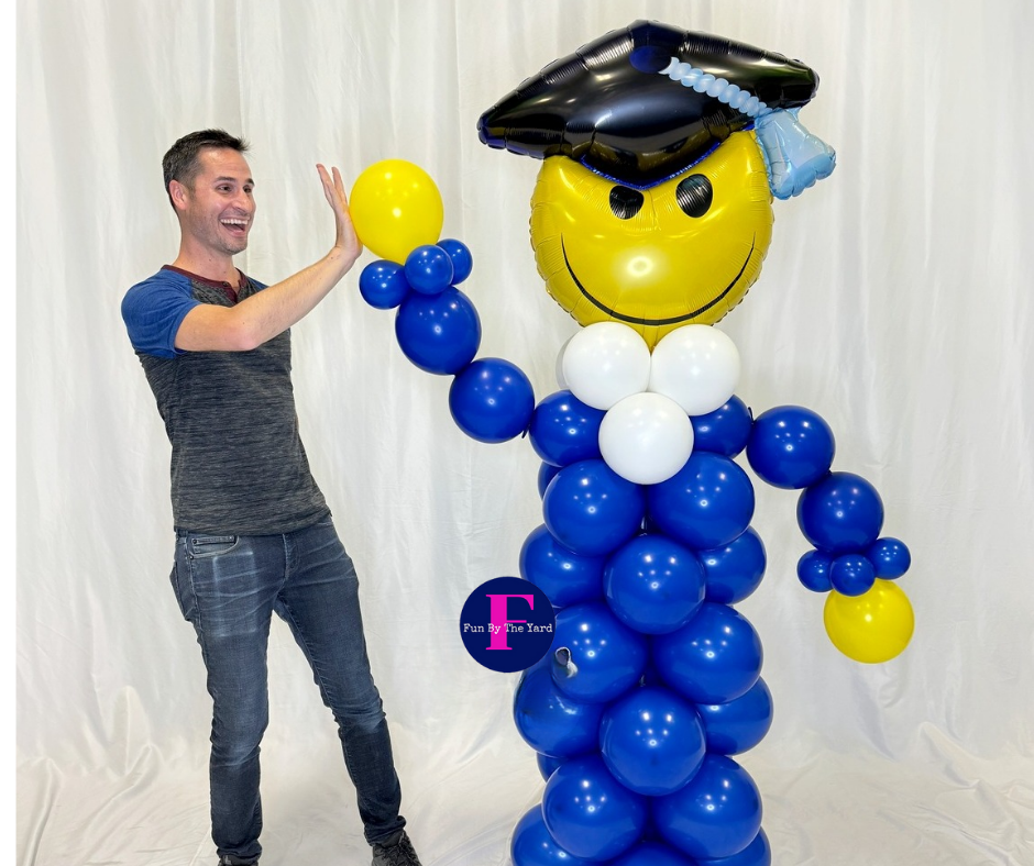 A man is standing next to a balloon sculpture of a graduate