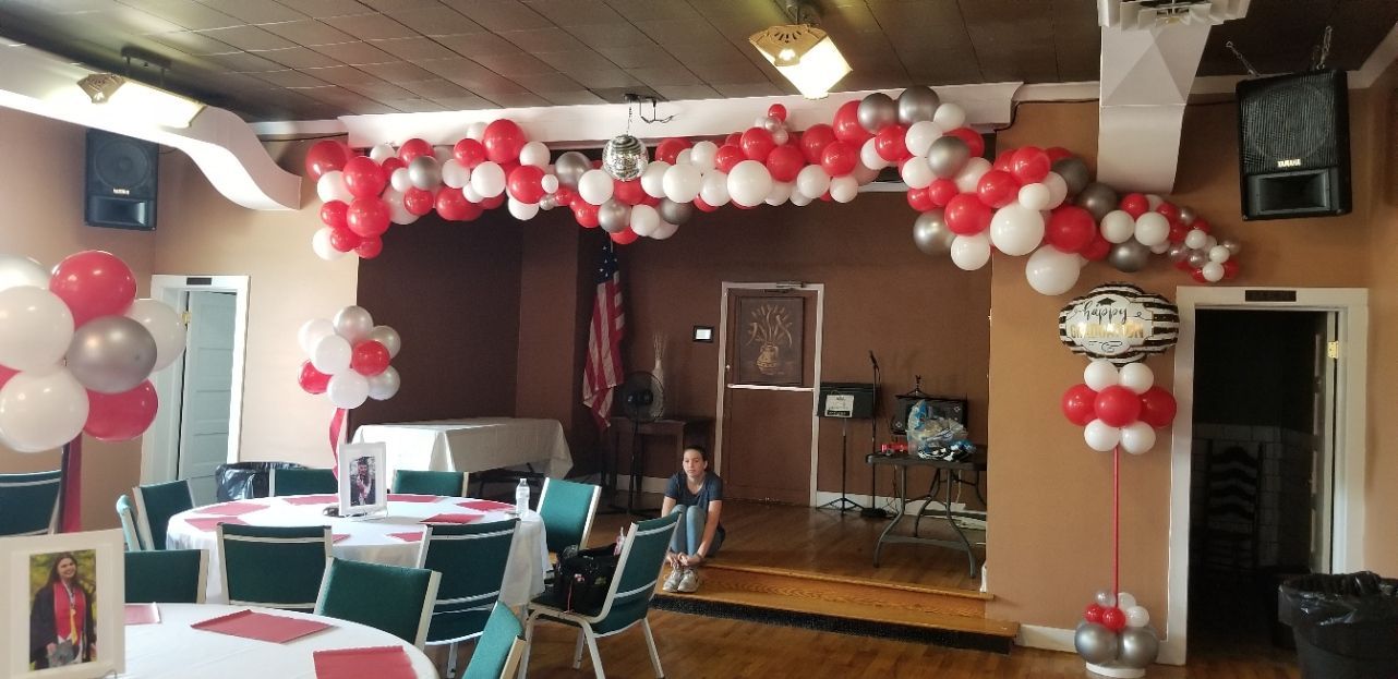 A room with tables and chairs and balloons hanging from the ceiling.