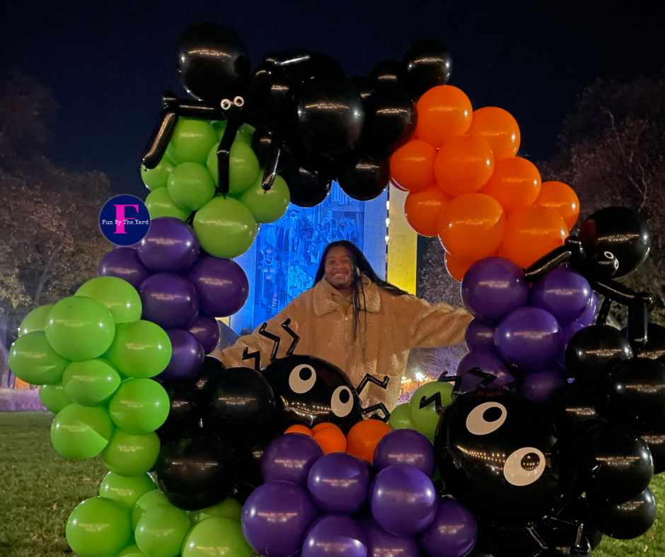 a woman is standing in front of a wreath of halloween balloons