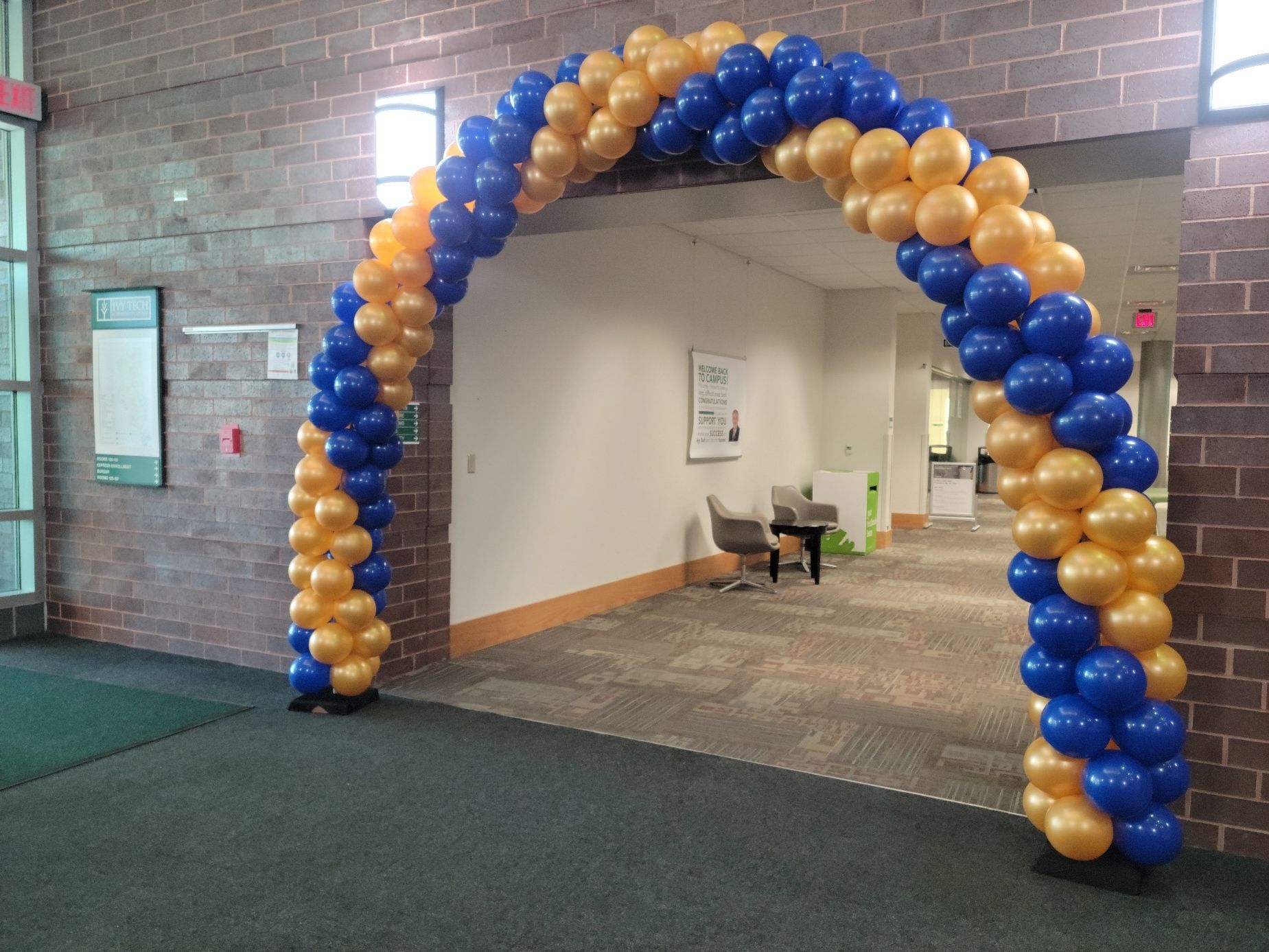 A blue and gold balloon arch in a hallway at Ivy Tech