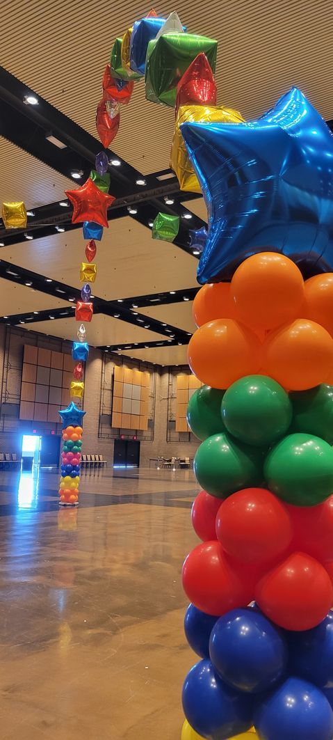 A bunch of colorful balloons are stacked on top of each other in a room.