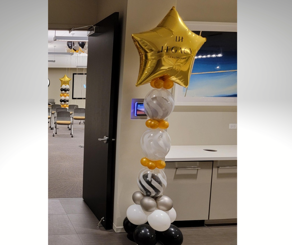 Balloon column with star topper inside office. Black, white, gold, and marble balloons.