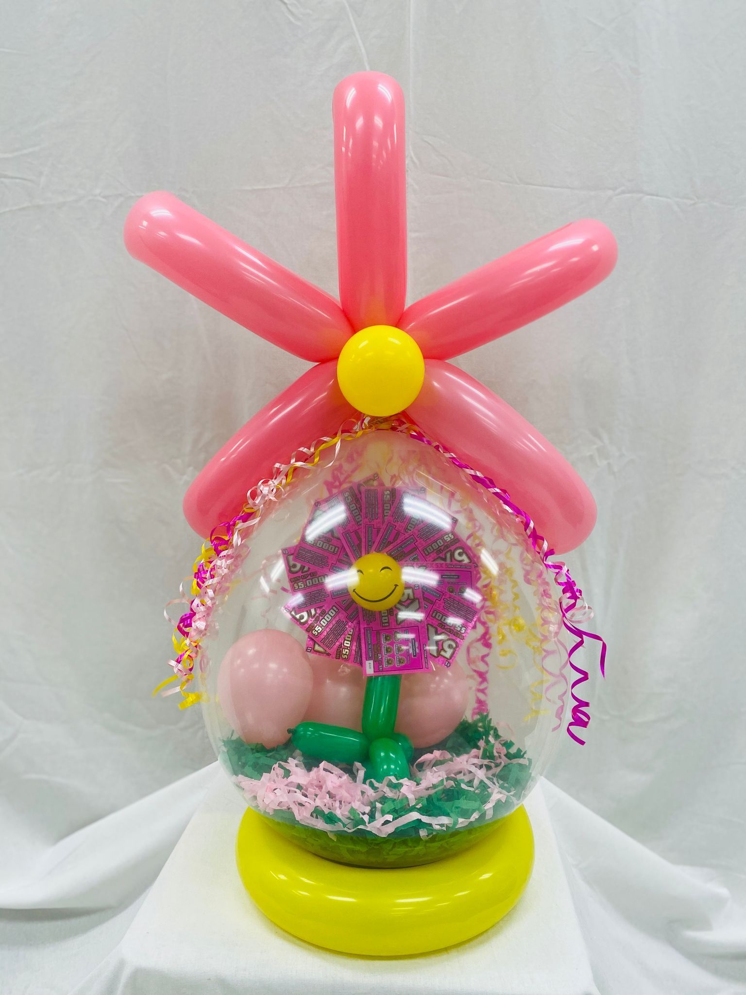 A flower made out of balloons with a smiley face on it