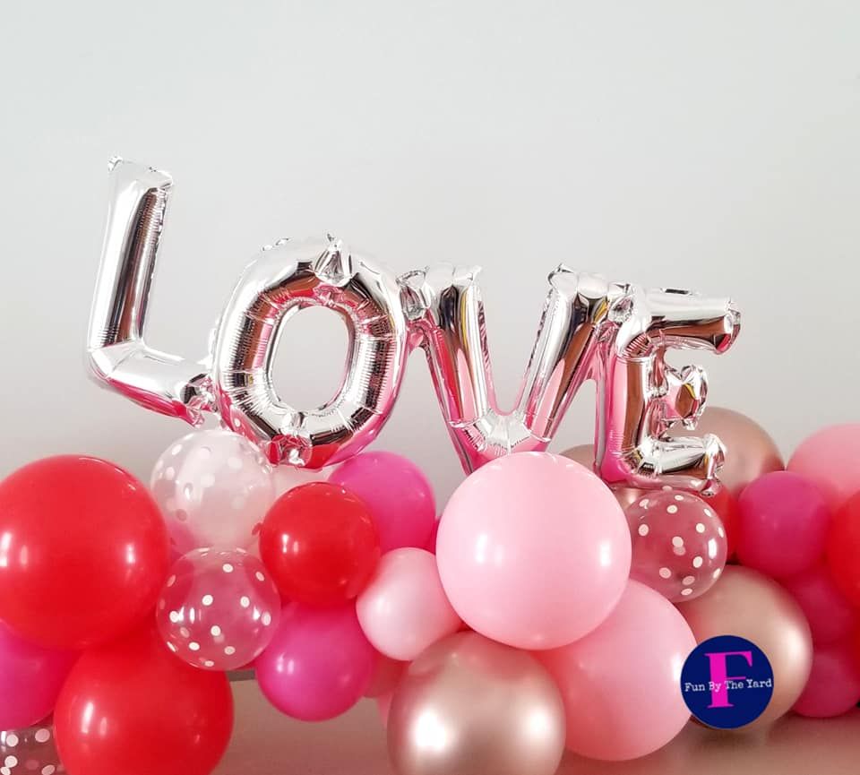 A bunch of pink and red balloons with the word love written on them