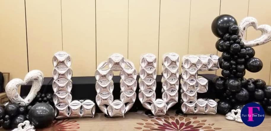 The word love is made of balloons and is surrounded by black and white balloons.