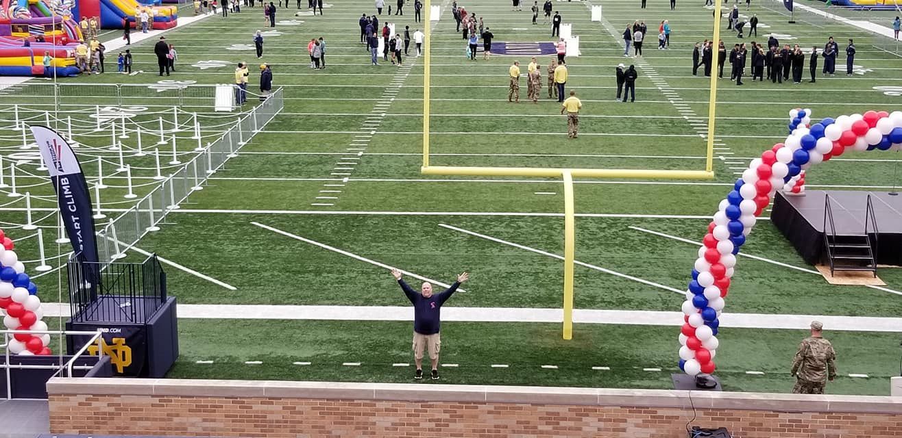 A man is standing on a football field with his arms in the air.