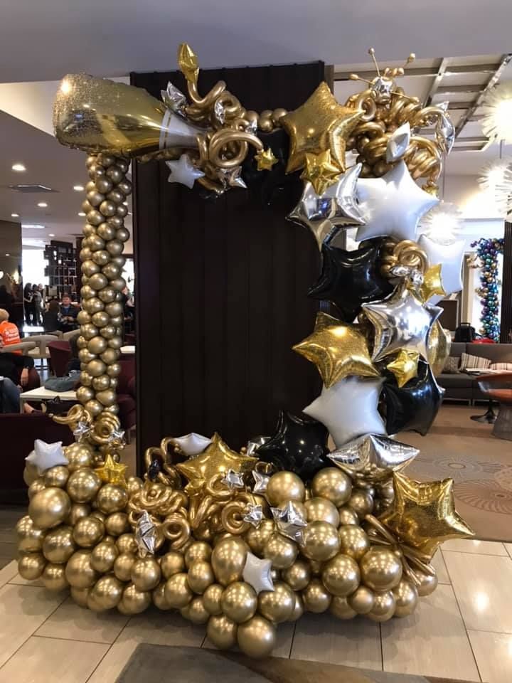 A picture frame made of gold and black balloons in a room.