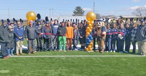 A group of people are standing on top of a football field with balloon columns