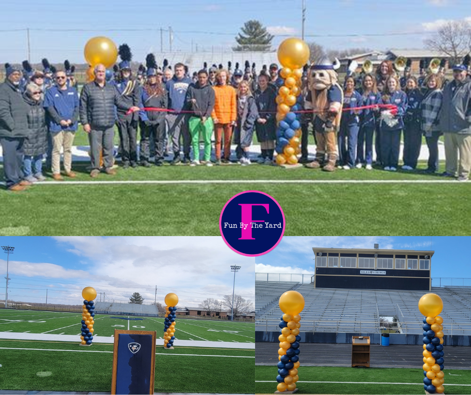 A group of people standing on a field with balloons and a mascot