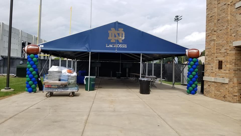 A blue tent with a football on top of it and balloons in front of it.