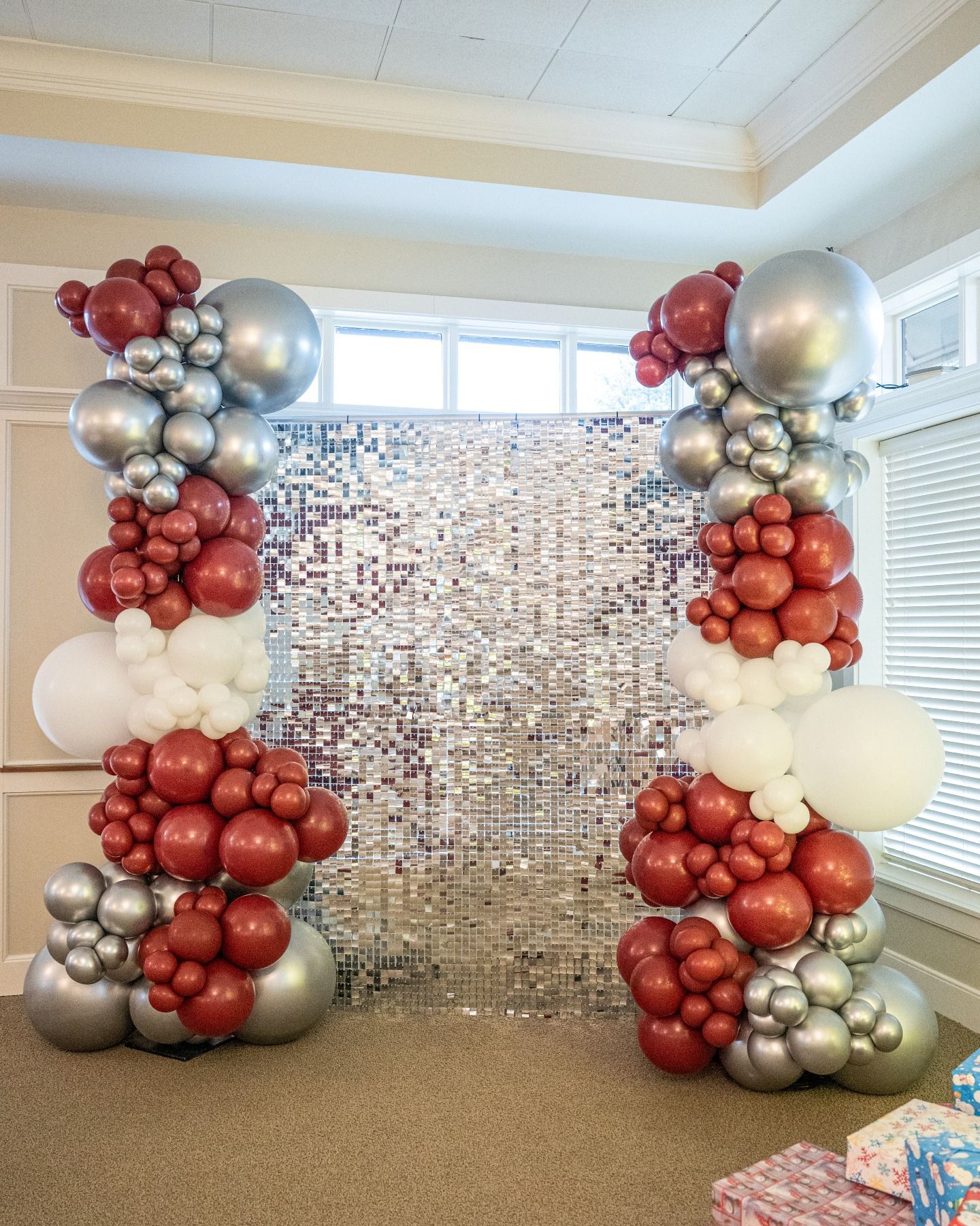 Balloon arch backdrop: red, white, silver balloons frame a mirrored wall.