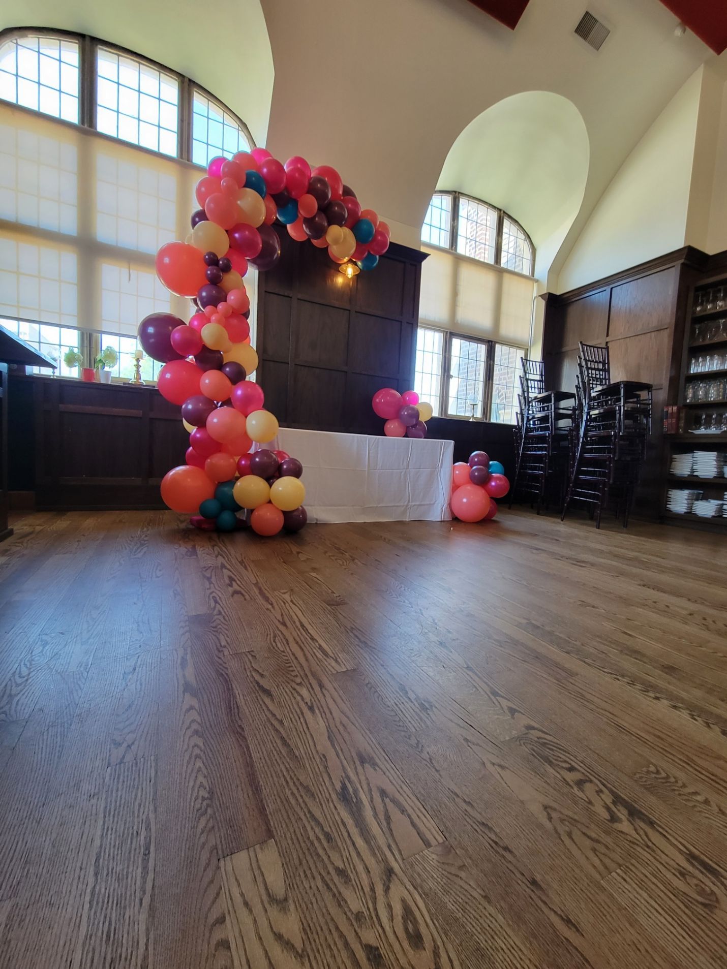 A bunch of balloons are sitting on a wooden floor in a room.