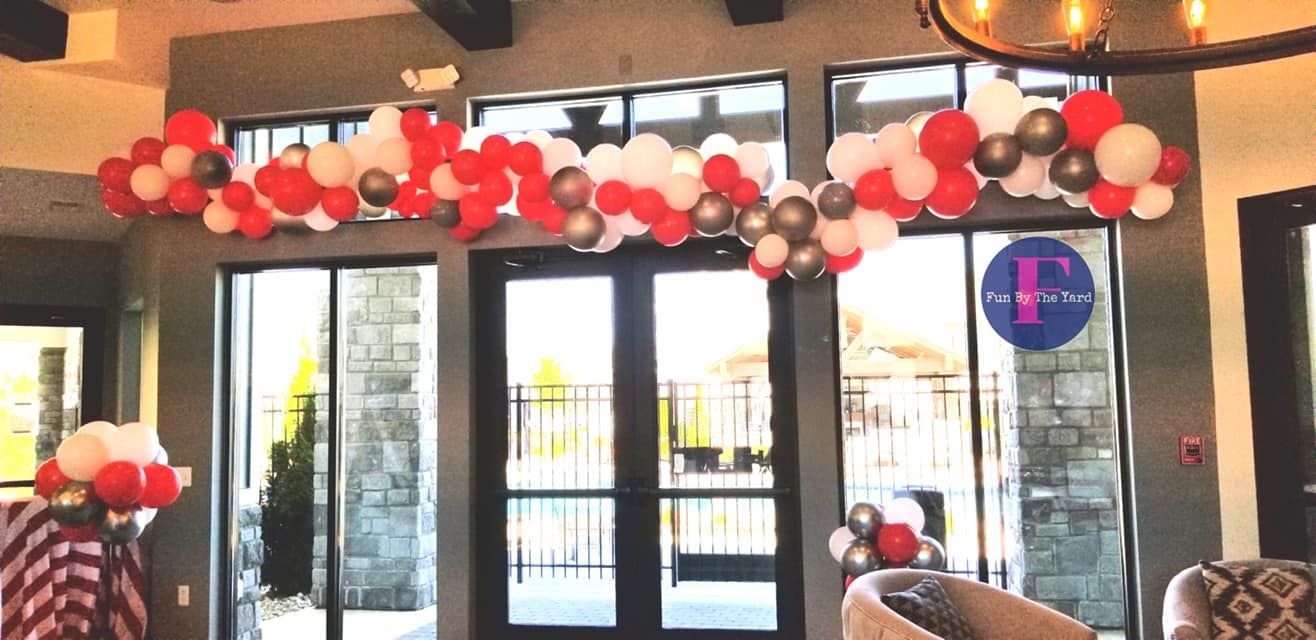 A room with red , white and silver balloons hanging from the ceiling.