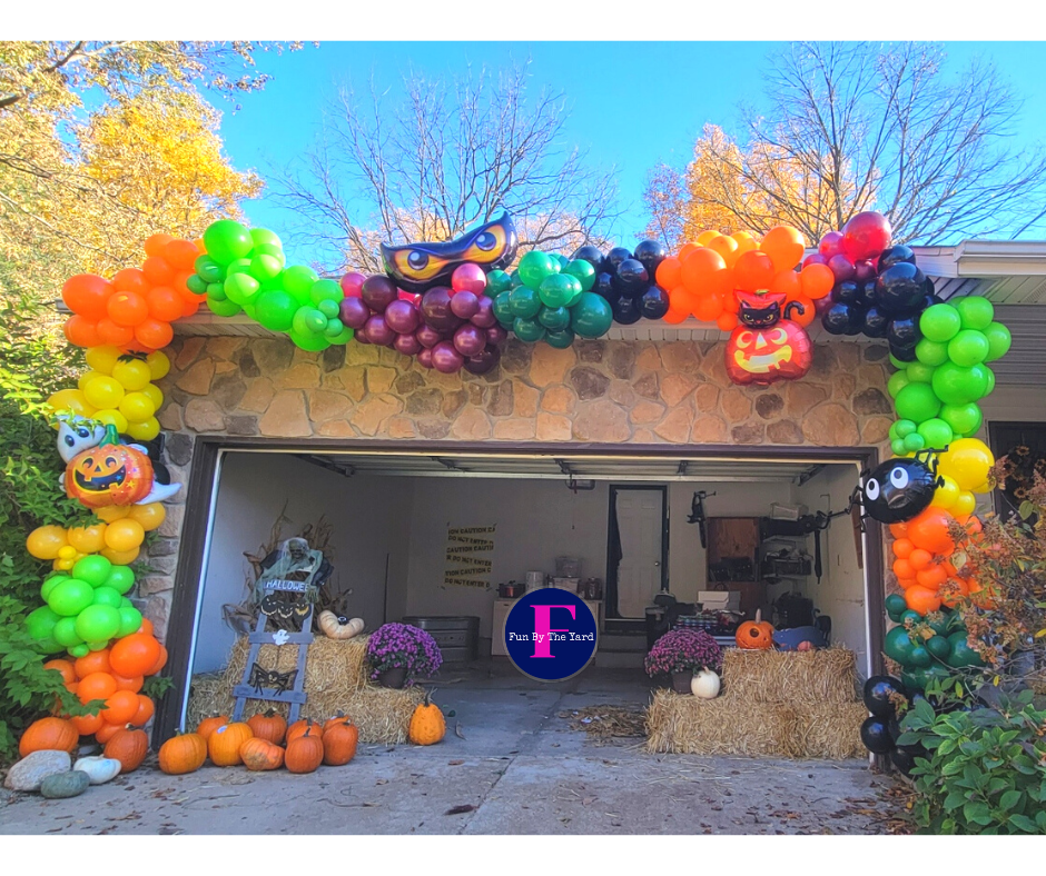 A garage door decorated for halloween with pumpkins and balloons.