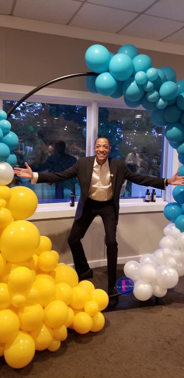 A man in a suit is standing in front of a balloon photo op