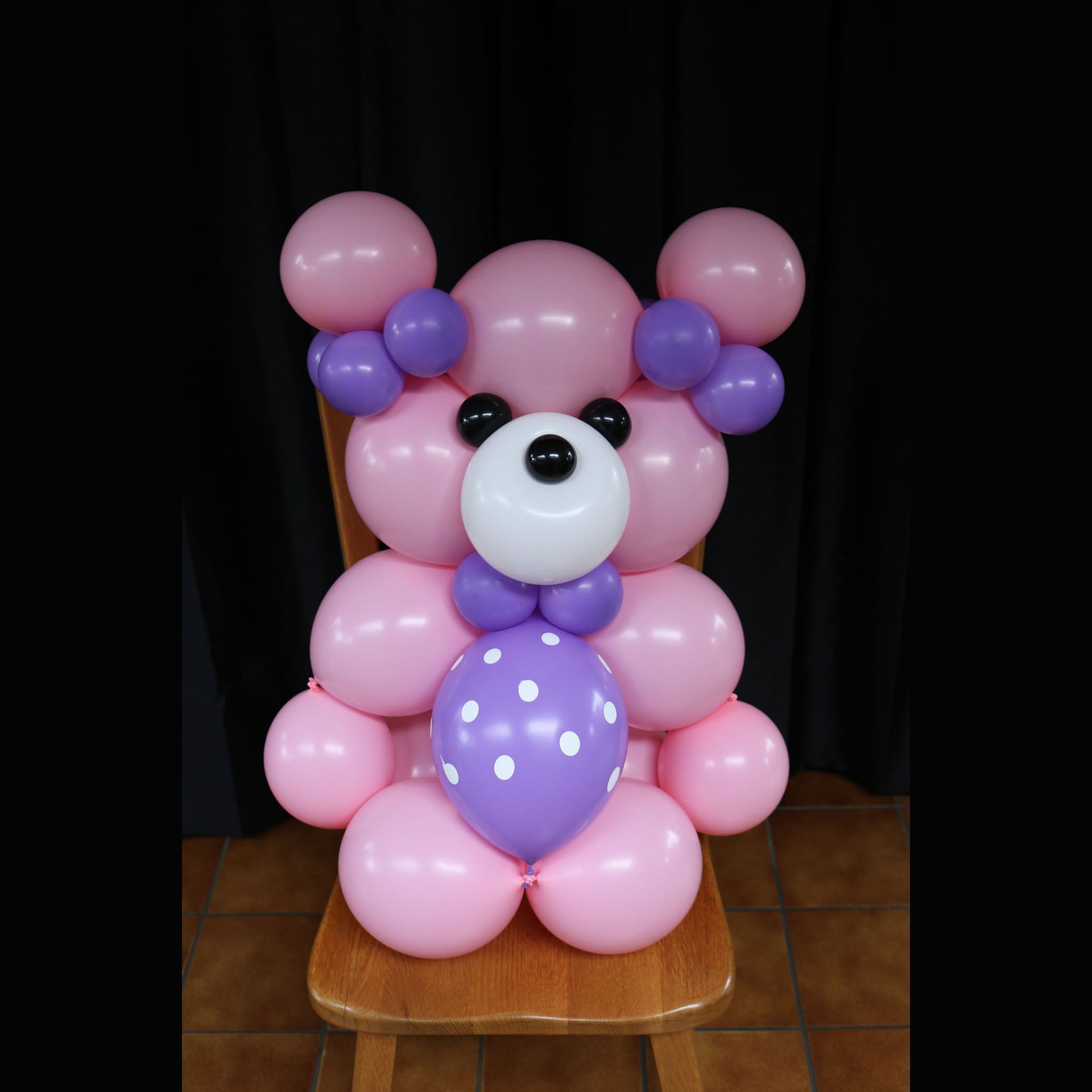 A teddy bear made out of pink and purple balloons