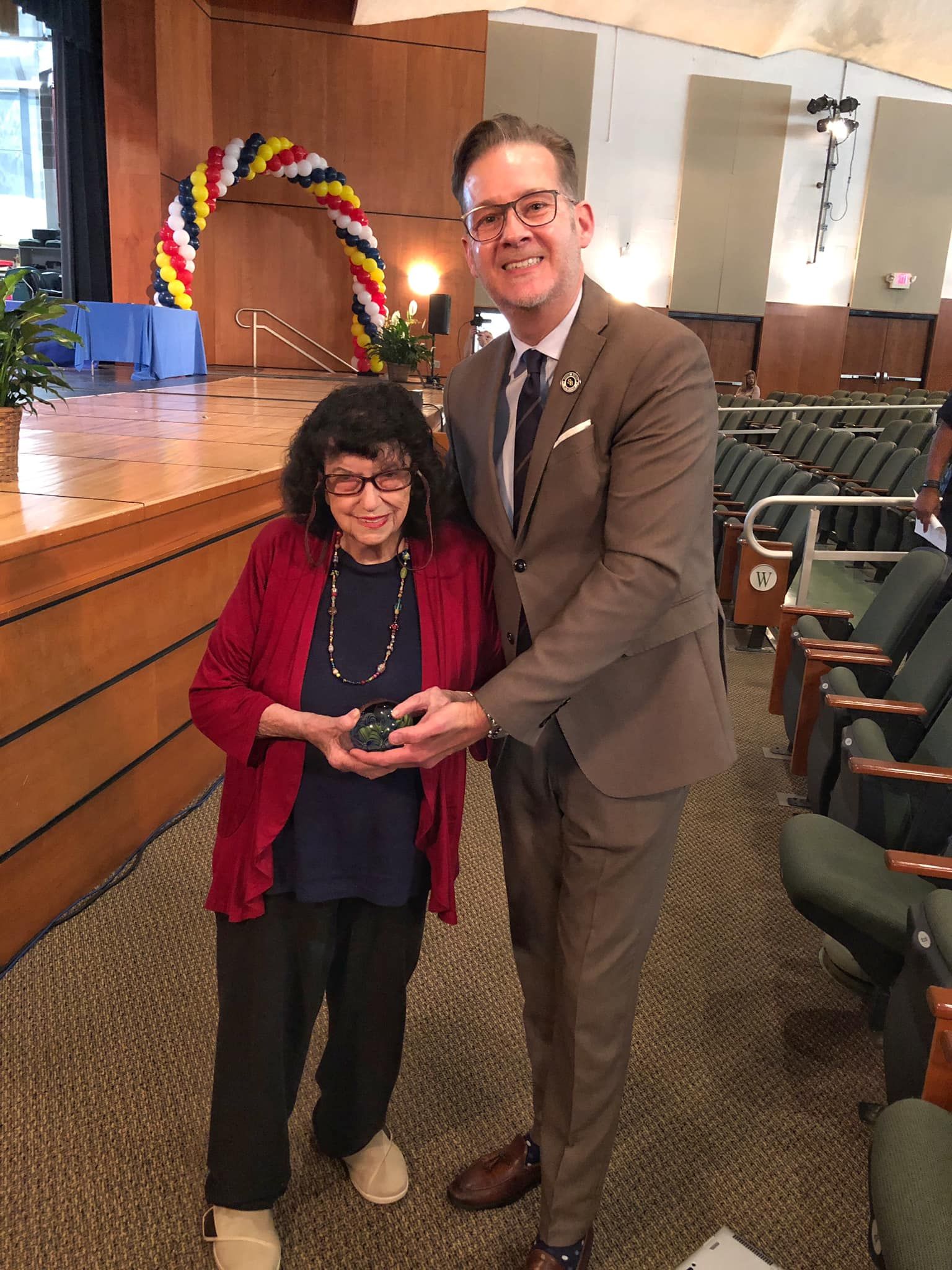 A man in a suit is giving an award to an older woman.