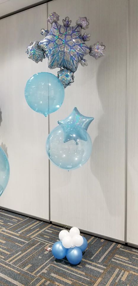 A bunch of blue and white balloons are sitting on the floor in a room.