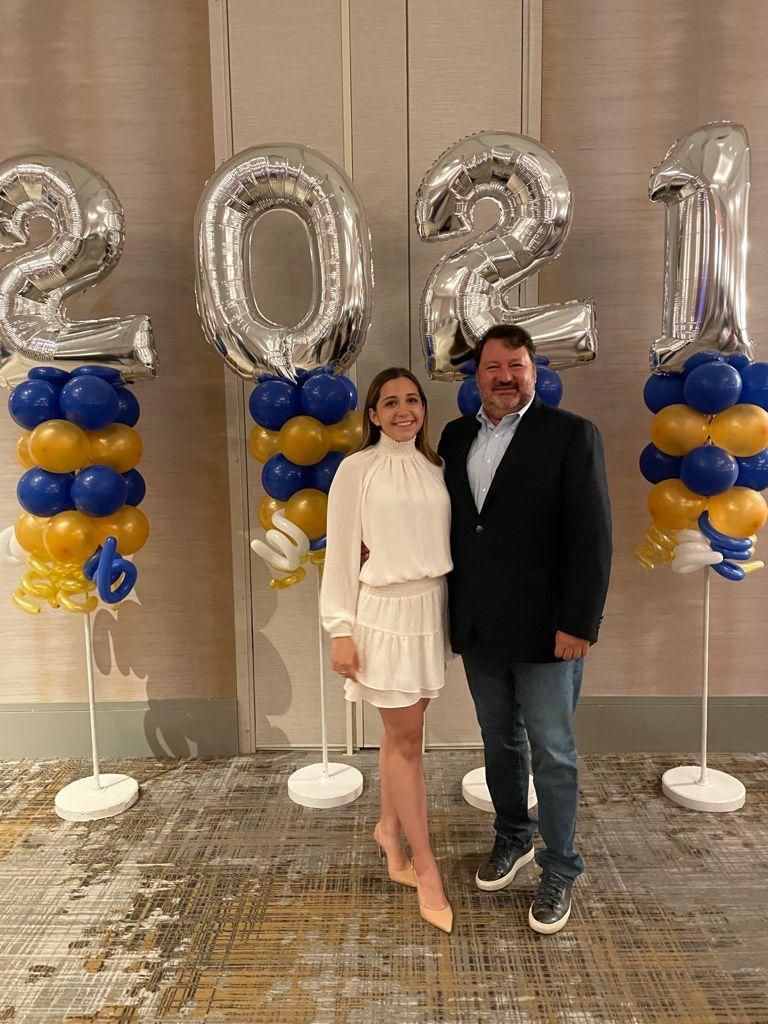 A man and a woman are standing next to each other in front of balloons.
