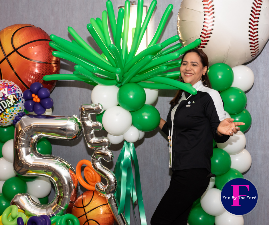 A woman is standing in front of a balloon arch with the number 5 on it