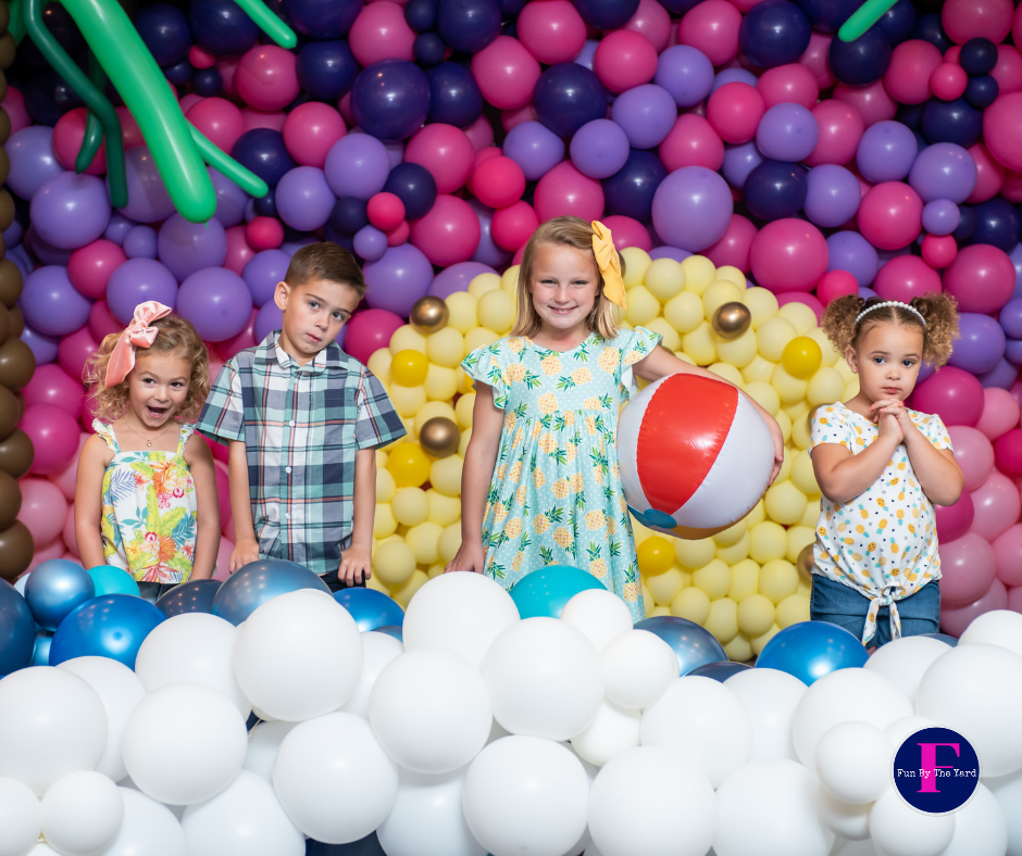 A group of children standing in front of a wall of balloons