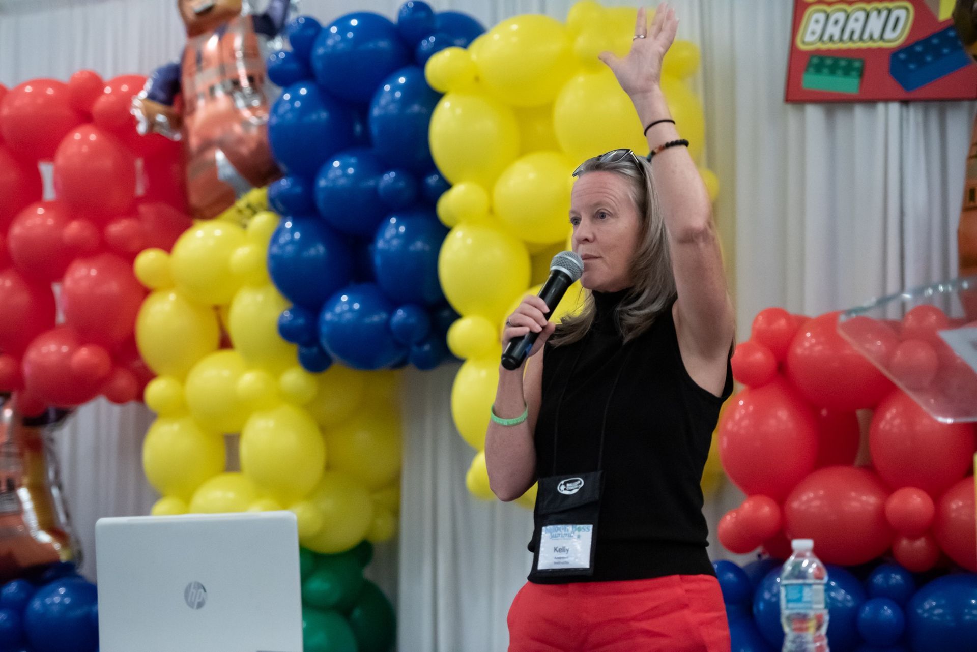 A woman is speaking into a microphone in front of balloons.