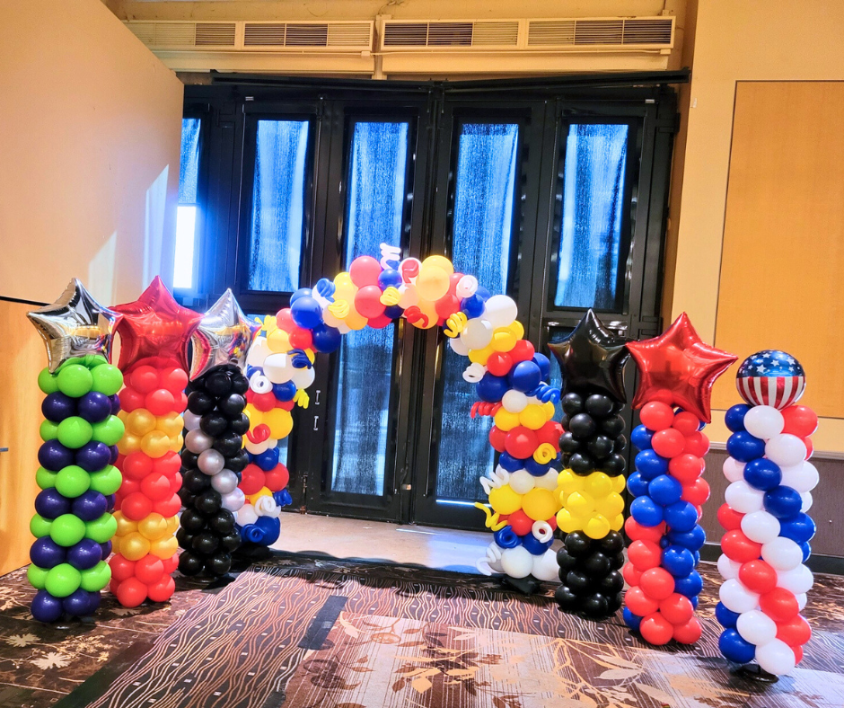 Super Hero themed balloon columns are lined up in a room