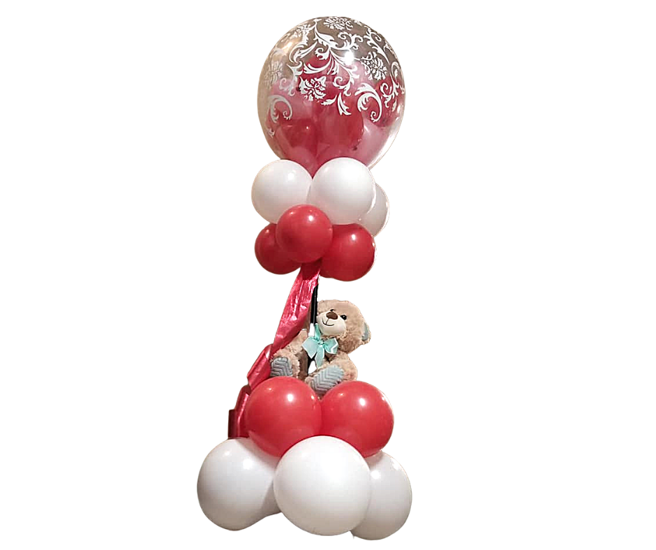 A teddy bear is sitting on top of a bunch of red and white balloons.