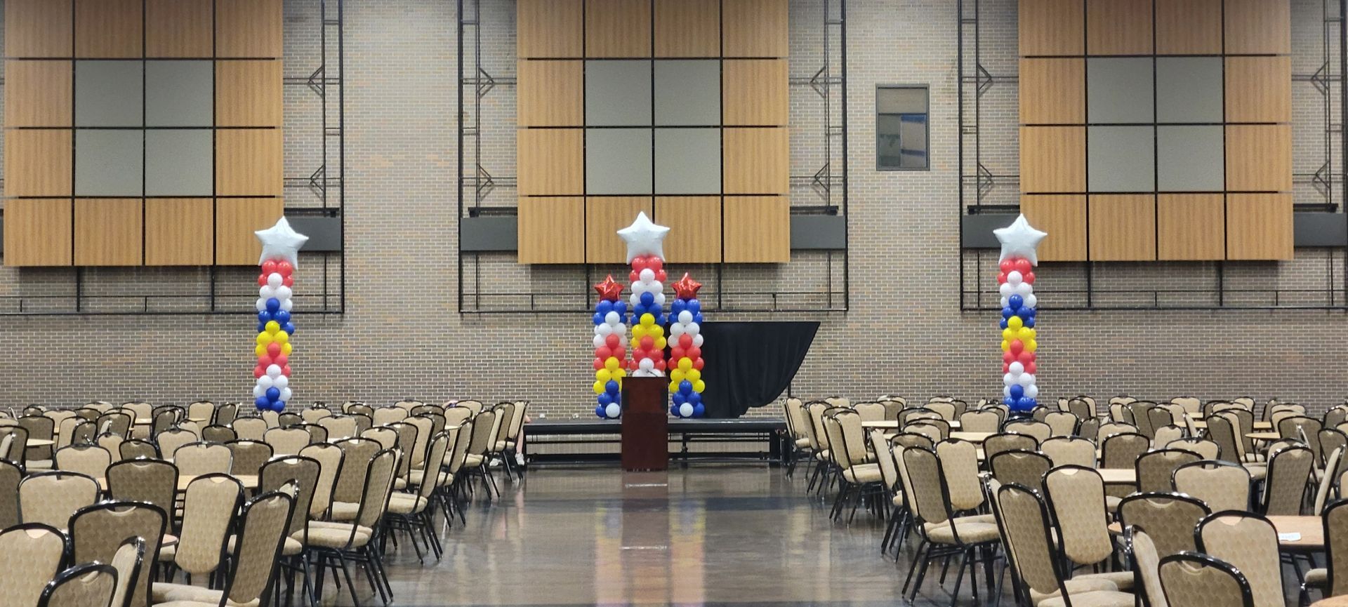 A large auditorium filled with chairs and balloons.