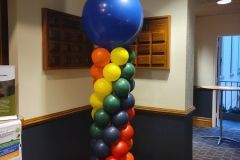 A row of colorful balloons on a pole in a room.