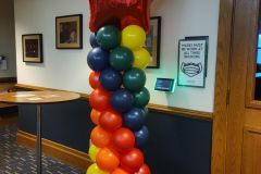 A column of balloons is sitting next to a table in a room.