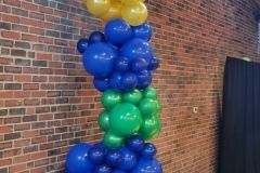 A bunch of balloons are stacked on top of each other in front of a brick wall.