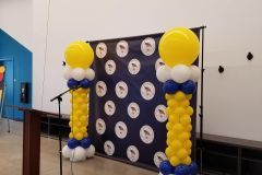 Empire styled balloon columns flanking a step and repeat backdrop for South Bend schools