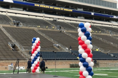 Red , white and blue balloons are lined up on a football field at Notre Dame.