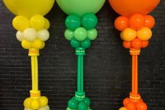 Three balloons are sitting on top of each other in front of a brick wall.  Empire themed balloon columns.