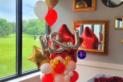 A bunch of balloons are sitting on a table in front of a window.  Balloon Marquee